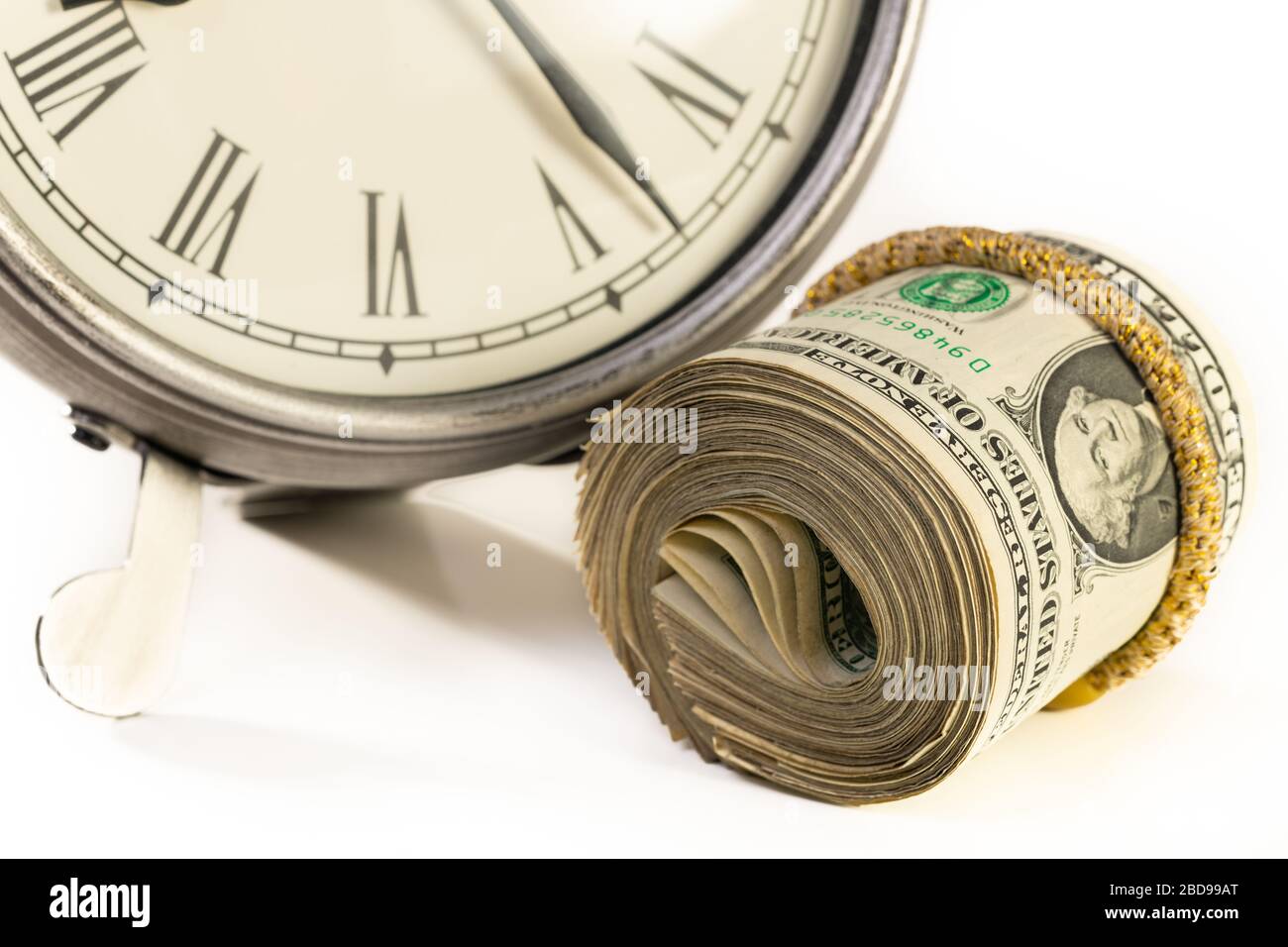 American money sitting near desktop clock. Time is money or financial planning concept. Stock Photo
