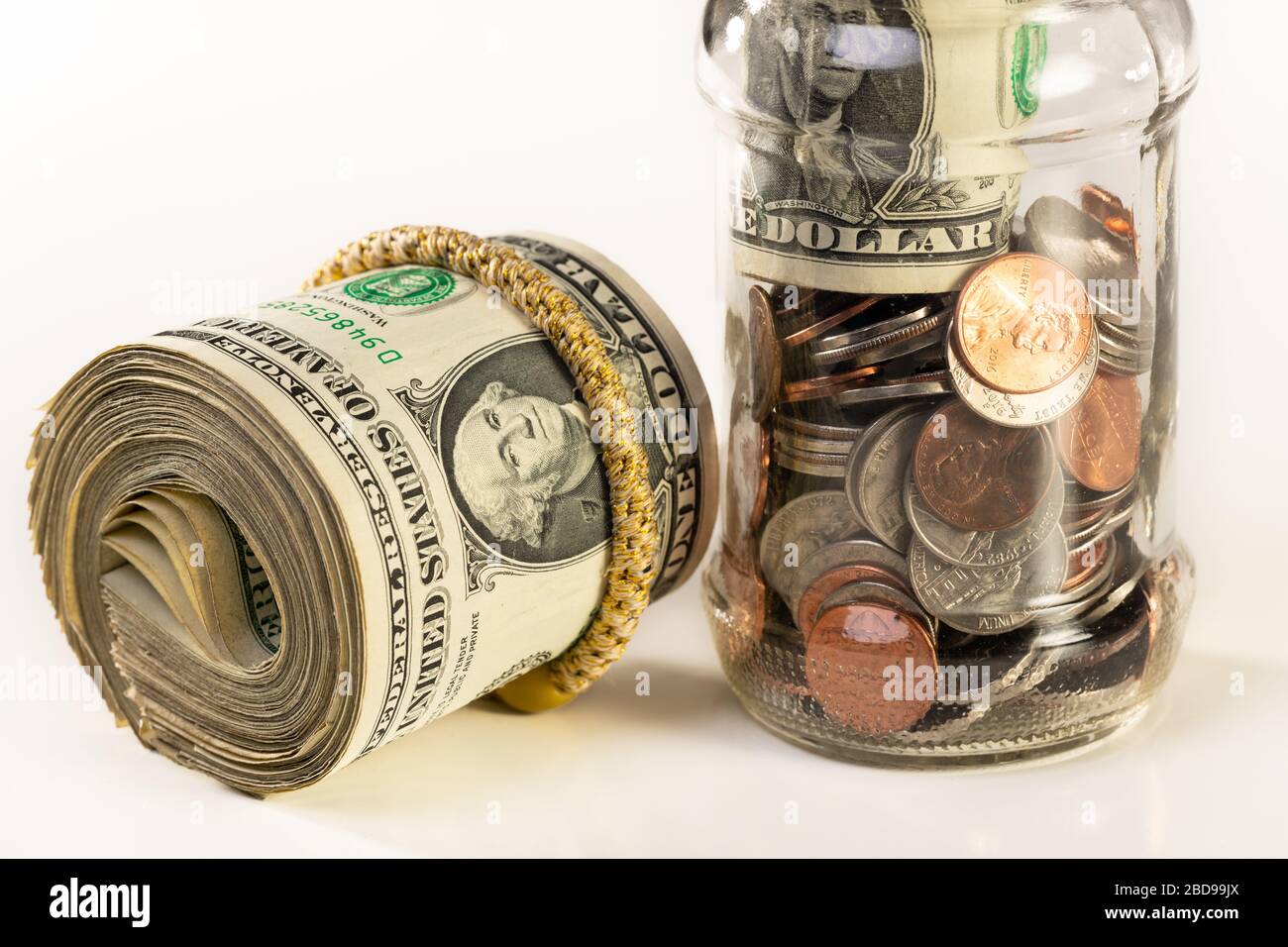 Glass jar and roll of money isolated on a white background. Stock Photo