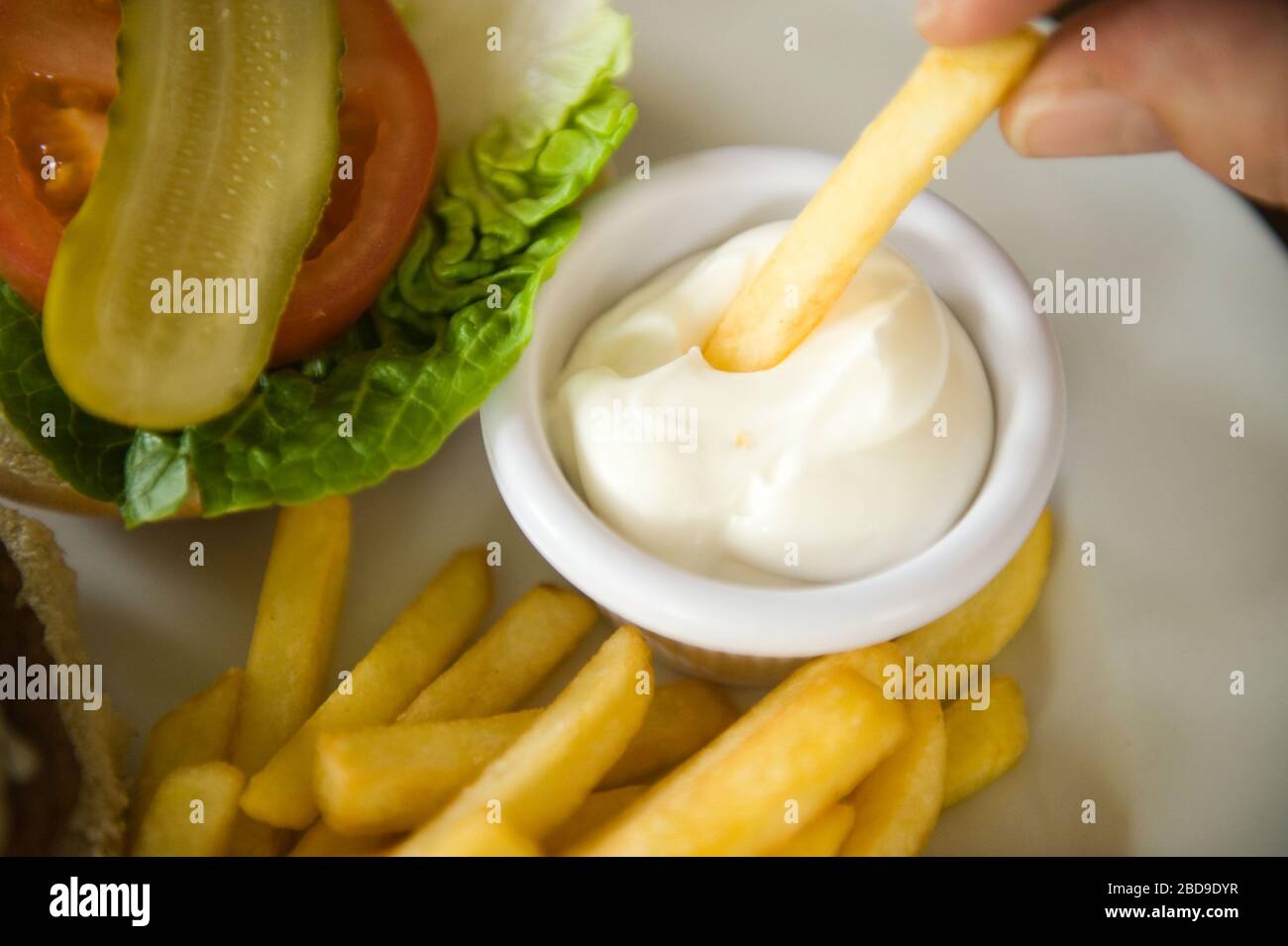 dipping potato chips or fries in a jar of mayonnaise Stock Photo Alamy