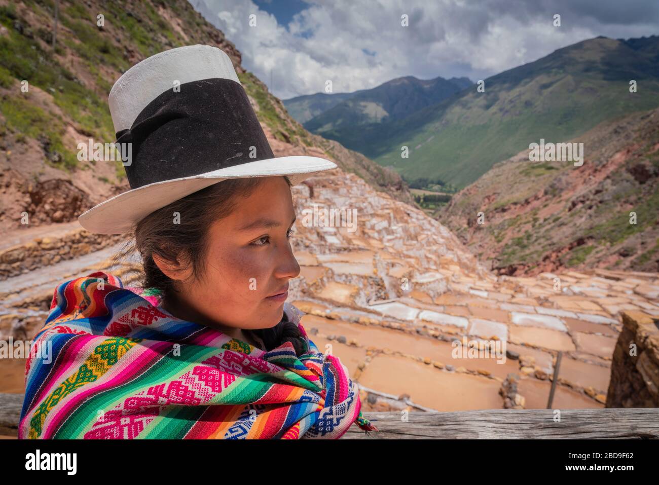 Quechua Mesbize (mixed race signified by white hat) at Salinaras District of Maras overlooking the salt ponds in Peru. Stock Photo