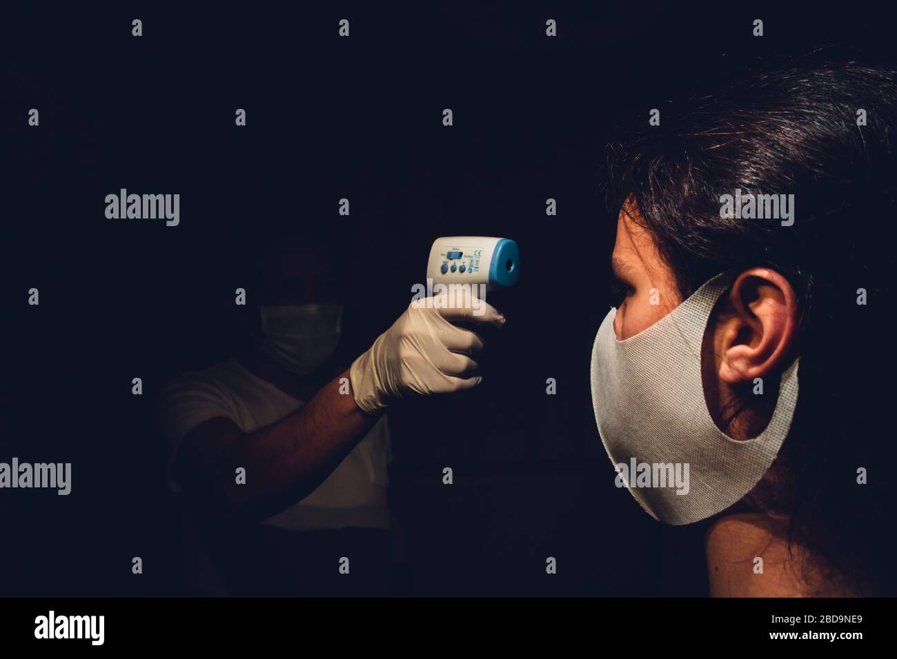 Medical employee measuring a healthy young adult's body temperature
