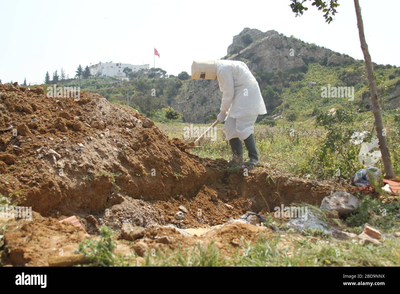 Municipality worker covers the grave with dust, wearing protective gear during the white operation.A grand burial named ‘white operation’ for corona virus victims. Tunisia has recorded a total of 650 infected cases and 23 deaths by the covid-19 disease. Stock Photo