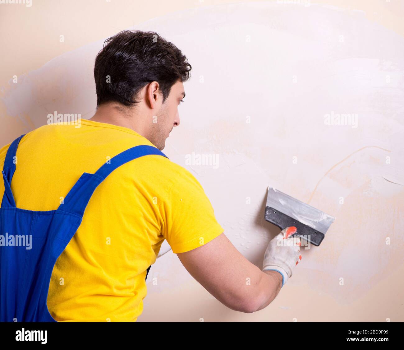 The young contractor employee applying plaster on wall Stock Photo