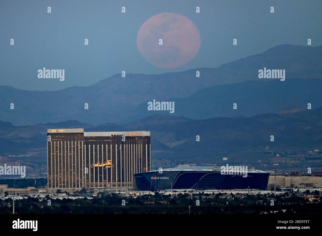 Las Vegas, Nevada, USA. 7th Apr, 2020. The super pink moon, the biggest supermoon of the year, rises over (L-R) Delano Las Vegas at Mandalay Bay Resort and Casino, Mandalay Bay Resort and Casino and the under construction Allegiant Stadium on April 7, 2020 in Las Vegas, Nevada. The pink moon got its name because the April full moon occurs at the same time as the pink wildflower Phlox subulata blooms in North America. A supermoon occurs when a full moon coincides with its perigee, which is its closest approach to the Earth. Credit: David Becker/ZUMA Wire/Alamy Live News Stock Photo