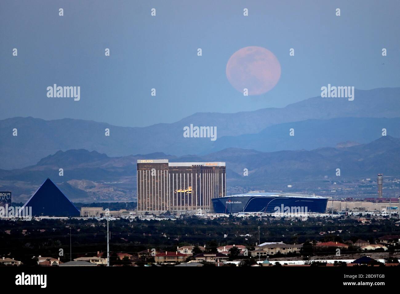 Las Vegas, Nevada, USA. 7th Apr, 2020. The super pink moon, the biggest supermoon of the year, rises over (L-R) Luxor Hotel and Casino, Delano Las Vegas at Mandalay Bay Resort and Casino, Mandalay Bay Resort and Casino and the under construction Allegiant Stadium on April 7, 2020 in Las Vegas, Nevada. The pink moon got its name because the April full moon occurs at the same time as the pink wildflower Phlox subulata blooms in North America. A supermoon occurs when a full moon coincides with its perigee, which is its closest approach to the Earth. Credit: David Becker/ZUMA Wire/Alamy Live News Stock Photo