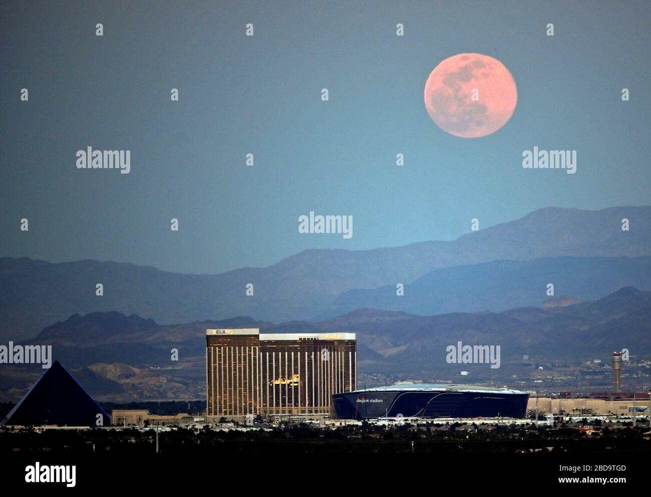 Las Vegas, Nevada, USA. 7th Apr, 2020. The super pink moon, the biggest supermoon of the year, rises over (L-R) Luxor Hotel and Casino, Delano Las Vegas at Mandalay Bay Resort and Casino, Mandalay Bay Resort and Casino and the under construction Allegiant Stadium on April 7, 2020 in Las Vegas, Nevada. The pink moon got its name because the April full moon occurs at the same time as the pink wildflower Phlox subulata blooms in North America. A supermoon occurs when a full moon coincides with its perigee, which is its closest approach to the Earth. Credit: David Becker/ZUMA Wire/Alamy Live News Stock Photo