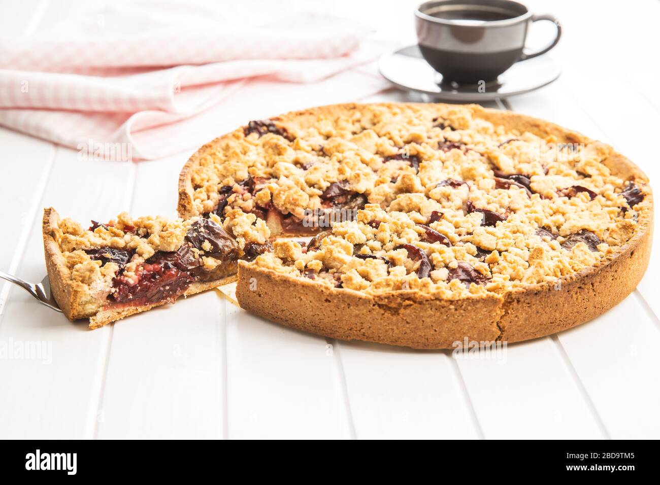 Sweet plum pie. Cut pie on white table. Stock Photo