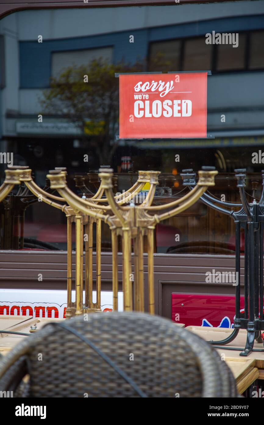 Neuwied, Germany - April 3, 2020: indicating label 'Sorry, we're closed' in the window of a closed pub with stacked chairs and tables in front based o Stock Photo