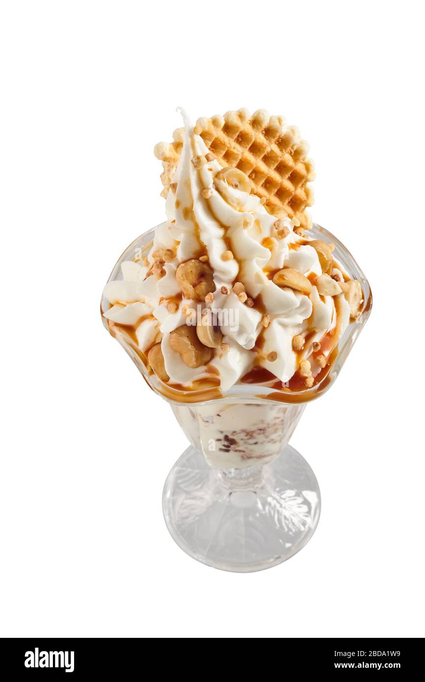 Serving of vanilla ice cream topped with nuts and drizzled with syrup garnished with a wafer