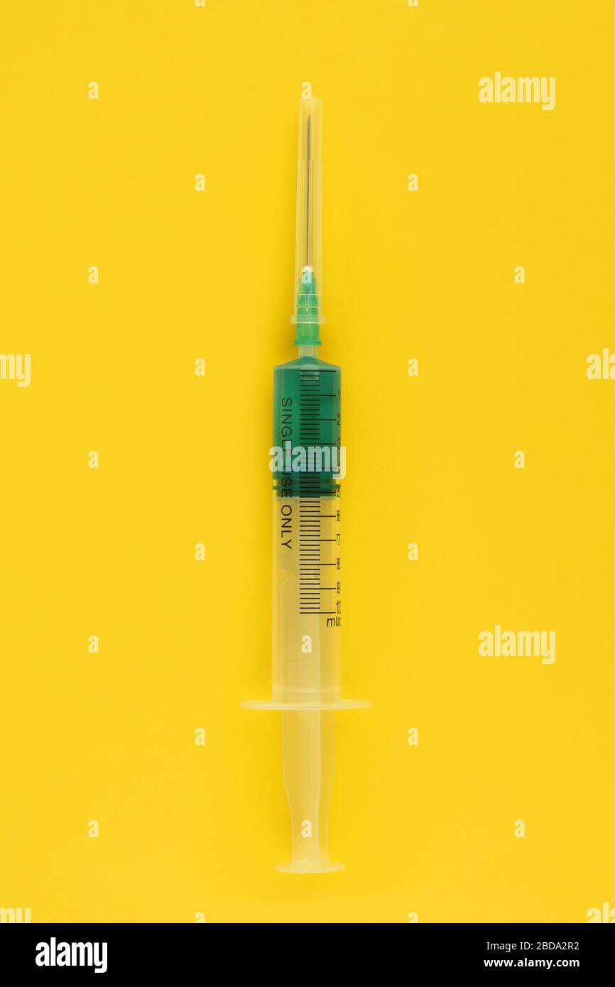 Syringe on a yellow background. Syringe with green medicinal fluid
