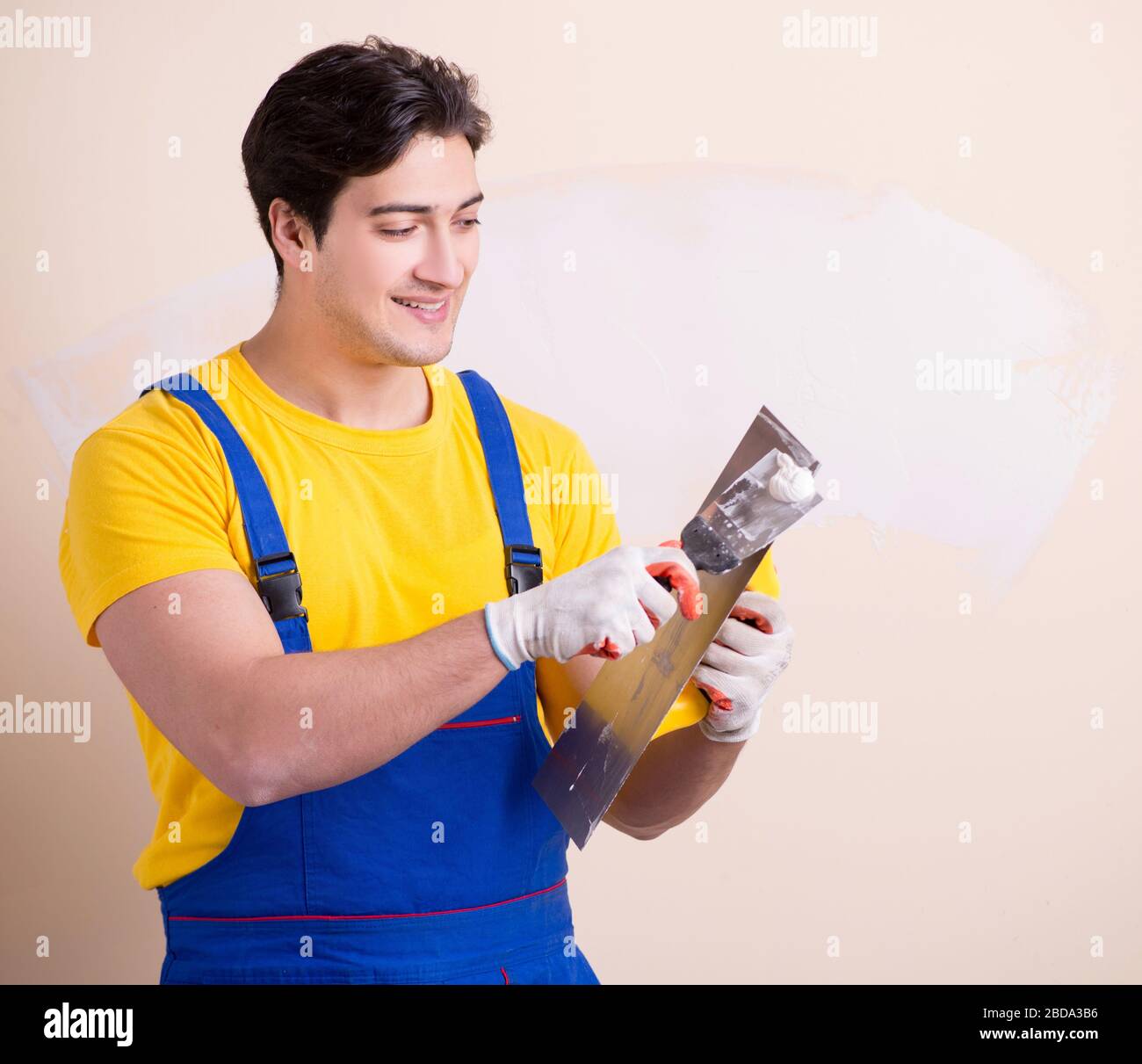 The young contractor employee applying plaster on wall Stock Photo