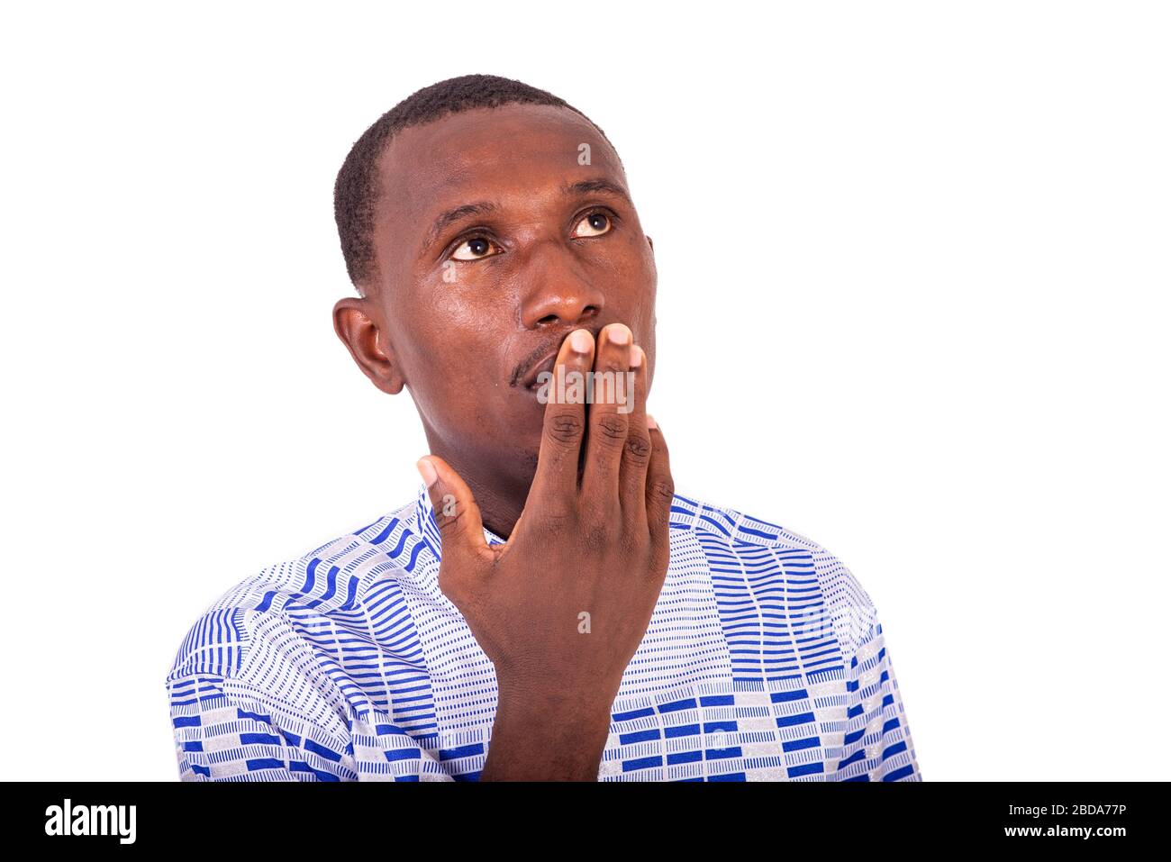 young man standing in shirt surprised, with hand on mouth looking upwards. Stock Photo