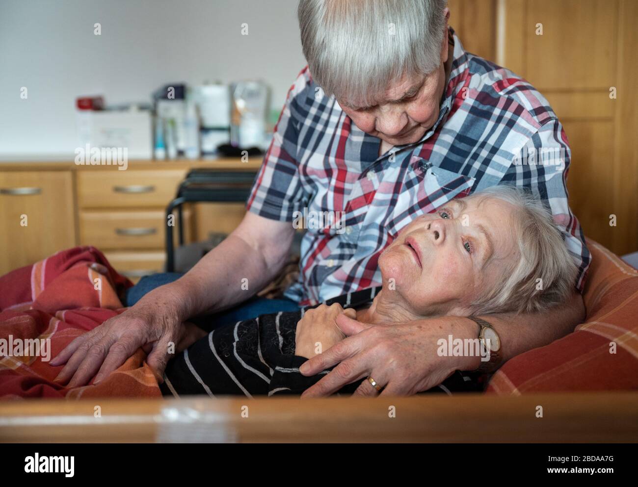 06 April 2020, North Rhine-Westphalia, Lünen: In his apartment, a caring  husband takes his wife, who is suffering from dementia and Parkinson's  disease, into his arms. In the midst of the Corona