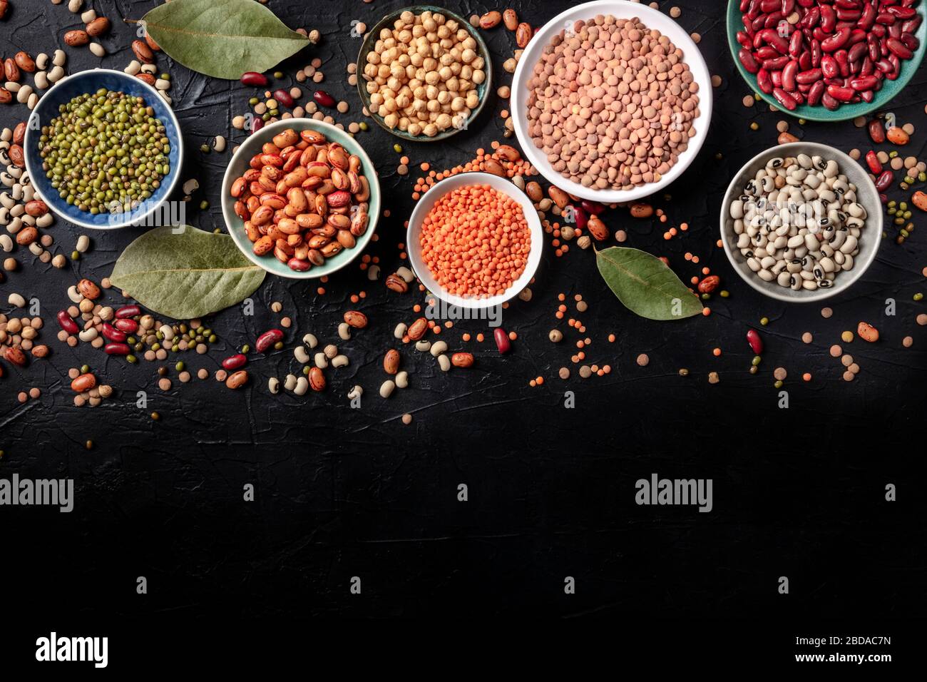 Legumes assortment, shot from above on a black background with copy space. Lentils, soybeans, chickpeas, red kidney beans, a vatiety of pulses Stock Photo