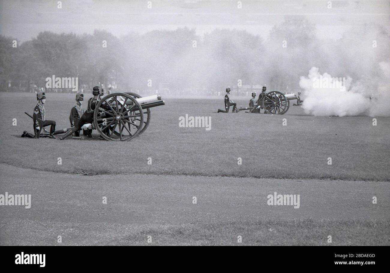 1960s, historical, smoke from the firing of ancient guns fills the air at a Royal gun Salute at Green Park near Buckingham Palace, Westminster, London, England. Gun salutes mark special royal occasions including the Queen's birthday and are a tradition display of British pageantry. Stock Photo