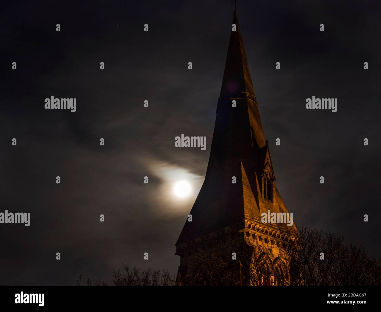 England North Yorkshire Knaresborough Full pink moon behind light cloud at Holy Trinity church spire Tuesday 7 April 2020 Stock Photo