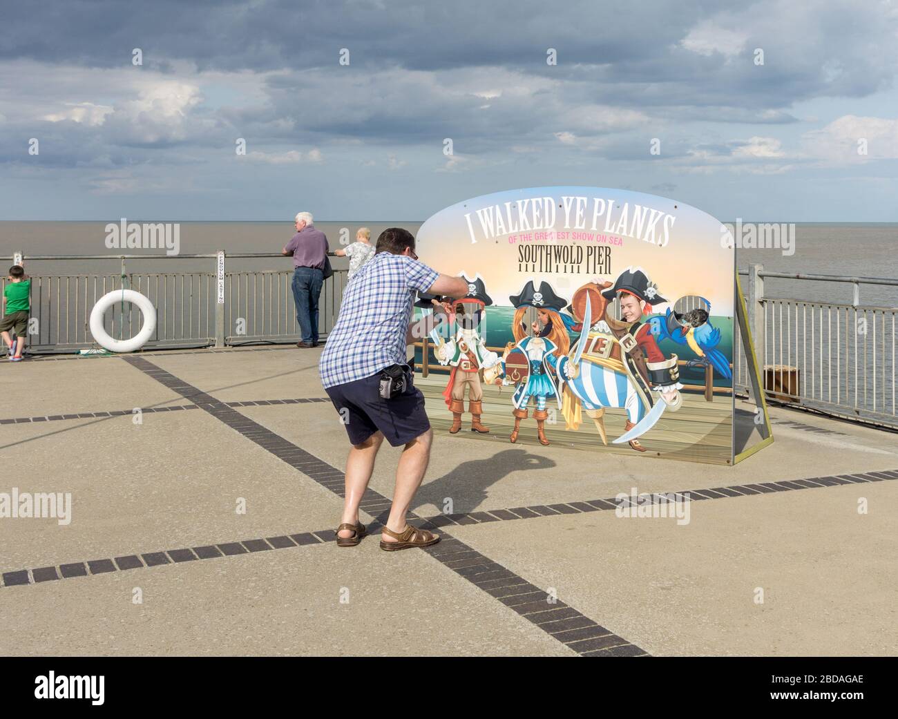 Man photographing his children through a pirate themed cut out board, Southwold Pier, Suffolk, UK Stock Photo