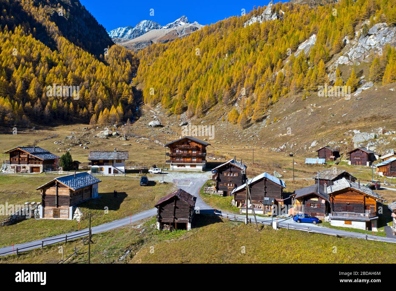 The hamlet of Satarma at the foot of a larch forest in bright autumn colors, Val d'Herens, Eringertal, Valais, Switzerland Stock Photo