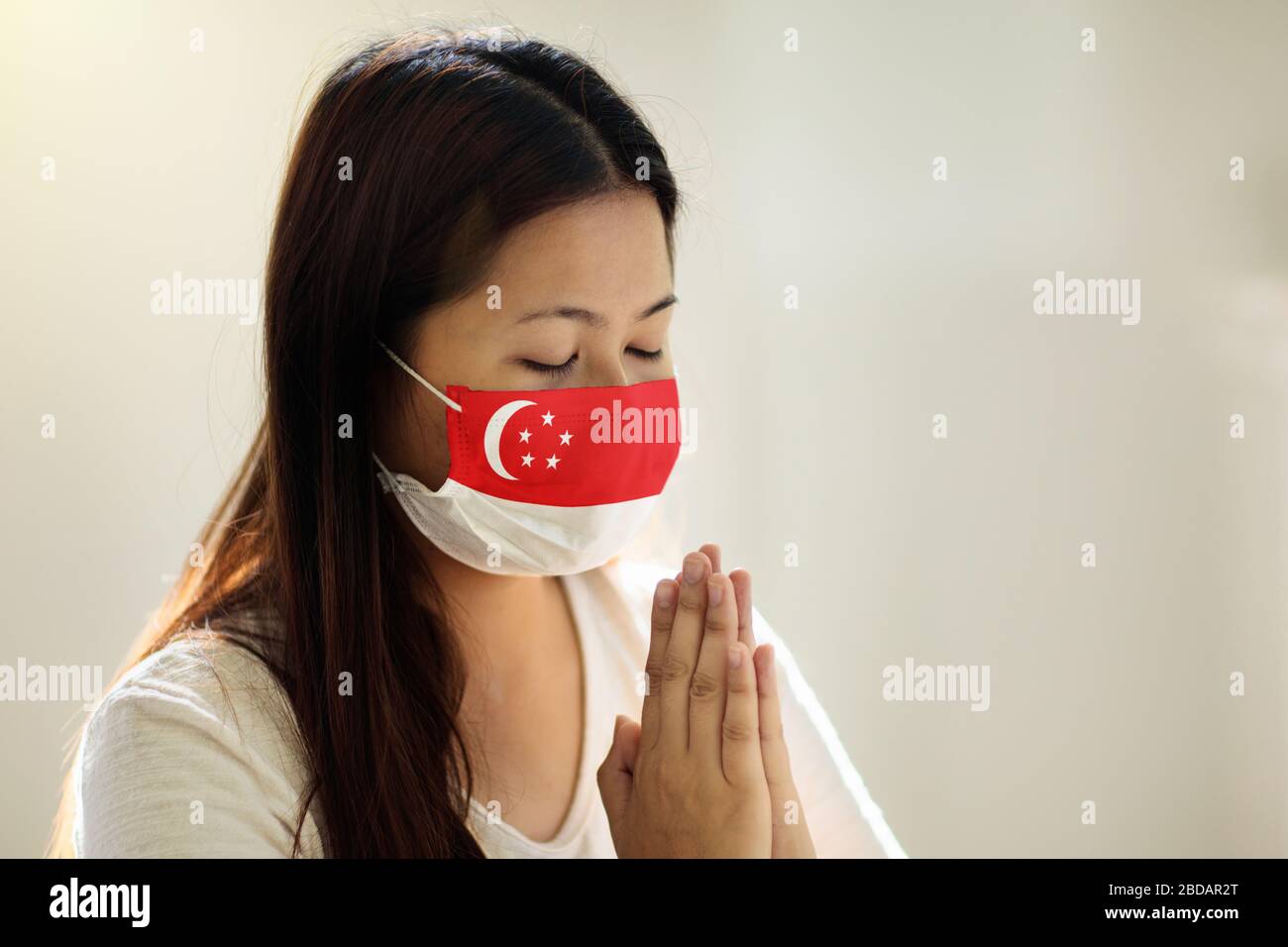 Pray for Singapore. Asian woman in face mask praying. Patient in