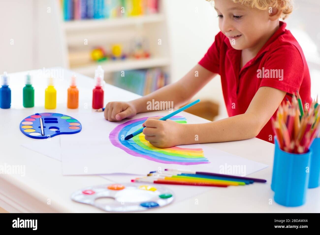 Kids paint. Child painting in white sunny study room. Little boy drawing rainbow. School kid