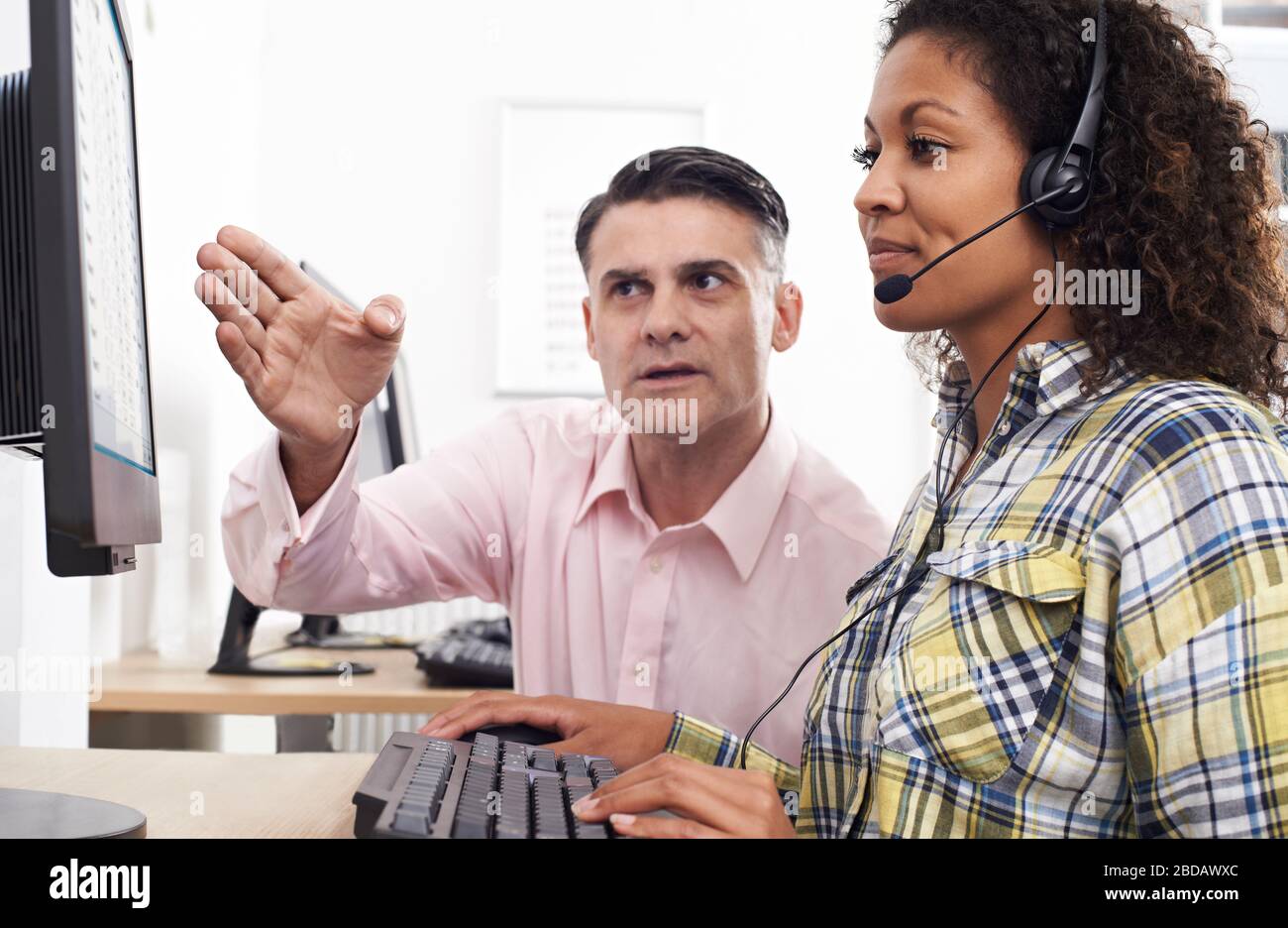 Businessman Training Female Employee Wearing Headset In Call Centre Office Stock Photo