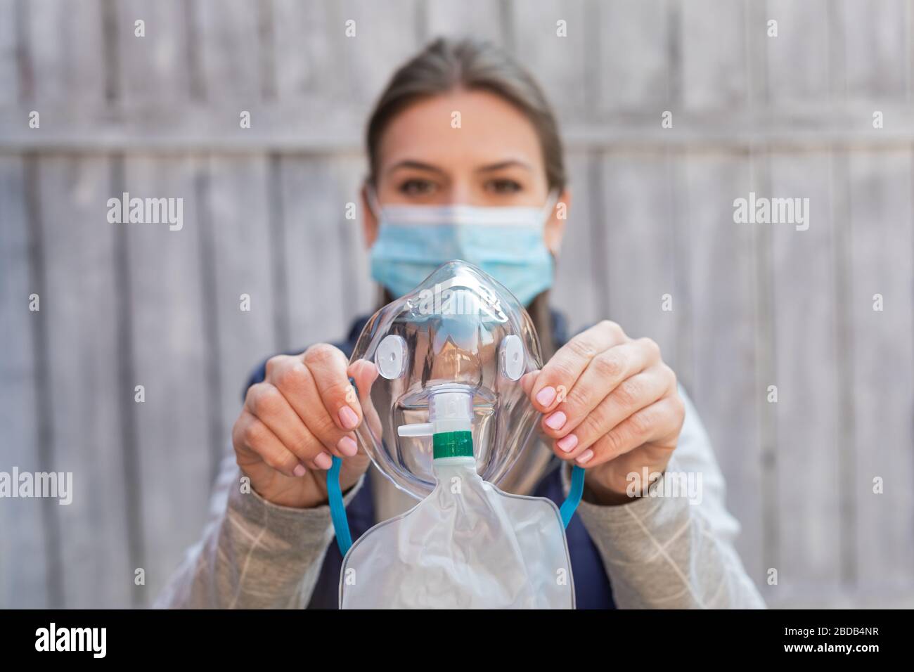 Woman wearing surgical mask is holding a medical oxygen mask outside coronavirus pandemic