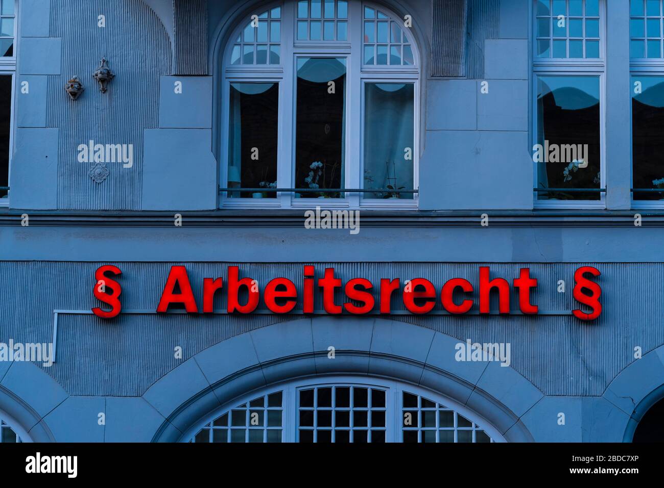 Illuminated lettering on a house wall, translated into English: labor ...