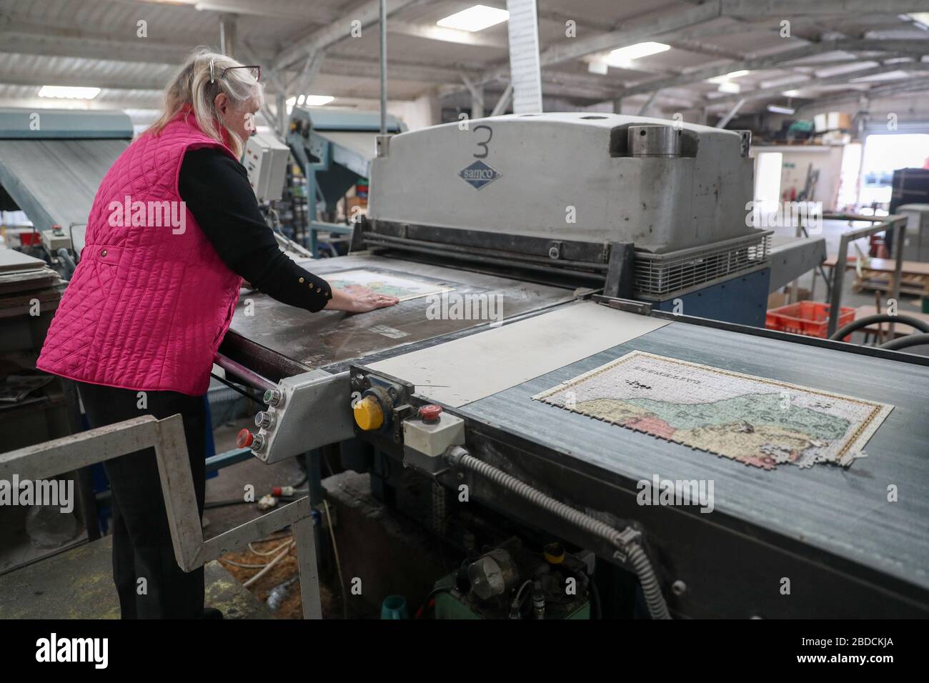 Julie Wilkins uses a machine to cut a jigsaw puzzle at JHG Jigsaws Ltd