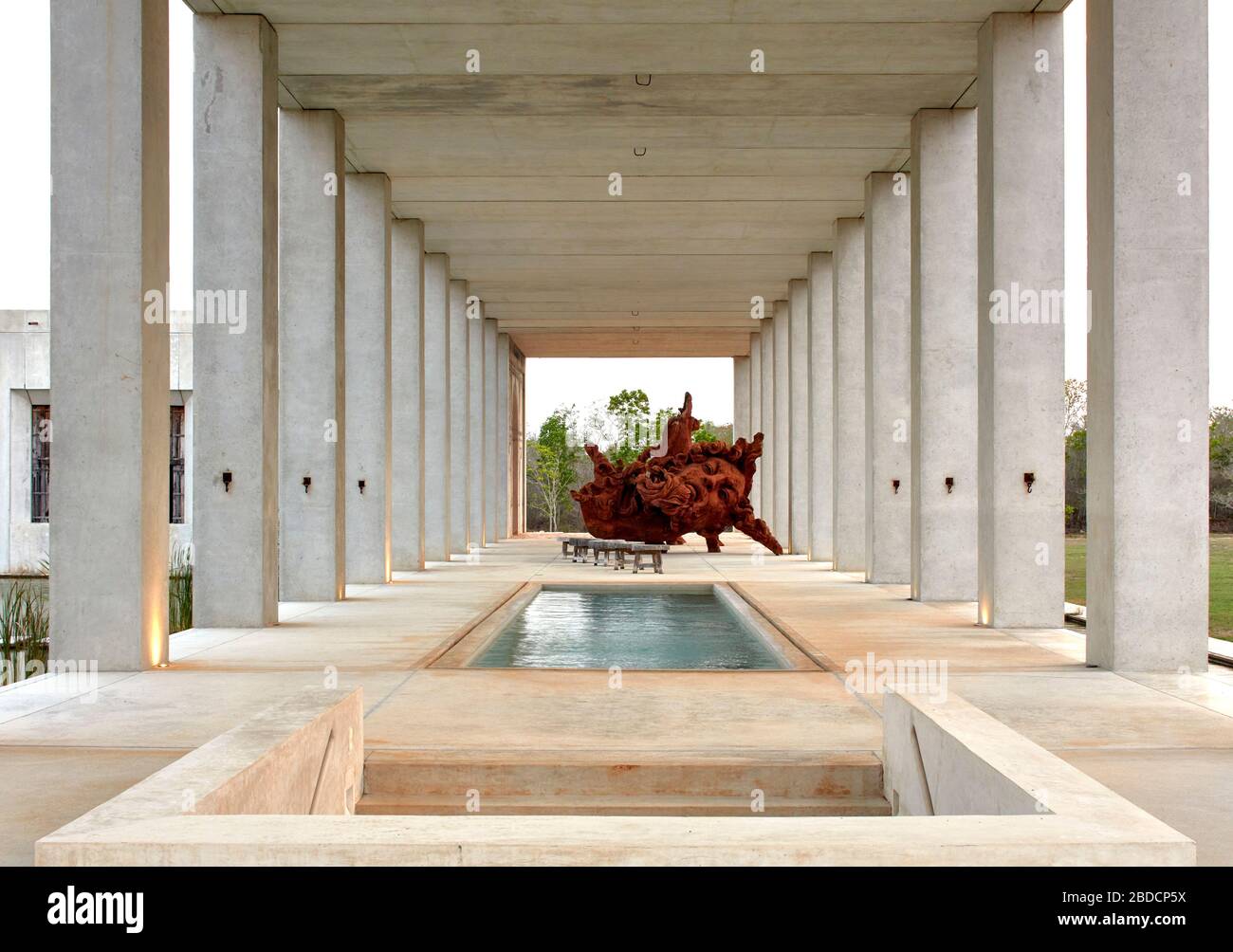 Colonnade with open air pool hall and  large sculpture beyond. Plantel Matilde, Yucatan, Mexico. Architect: Javier Marín and Arcadio Marín, 2020. Stock Photo