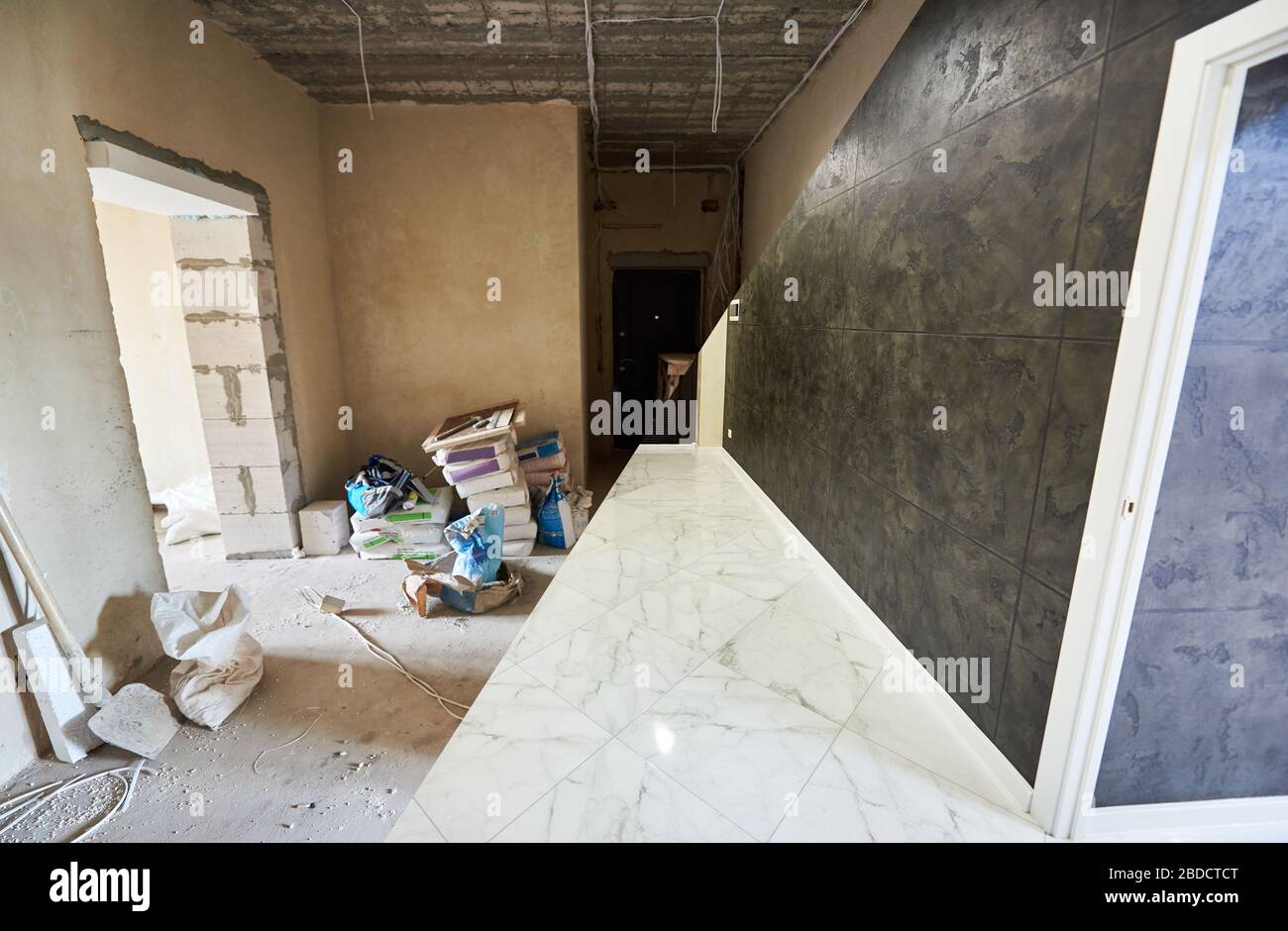 Messy dirty room at the beginning of reconstruction works vs clean shiny tiled part of a new room, white floor and black wall, renovation concept Stock Photo