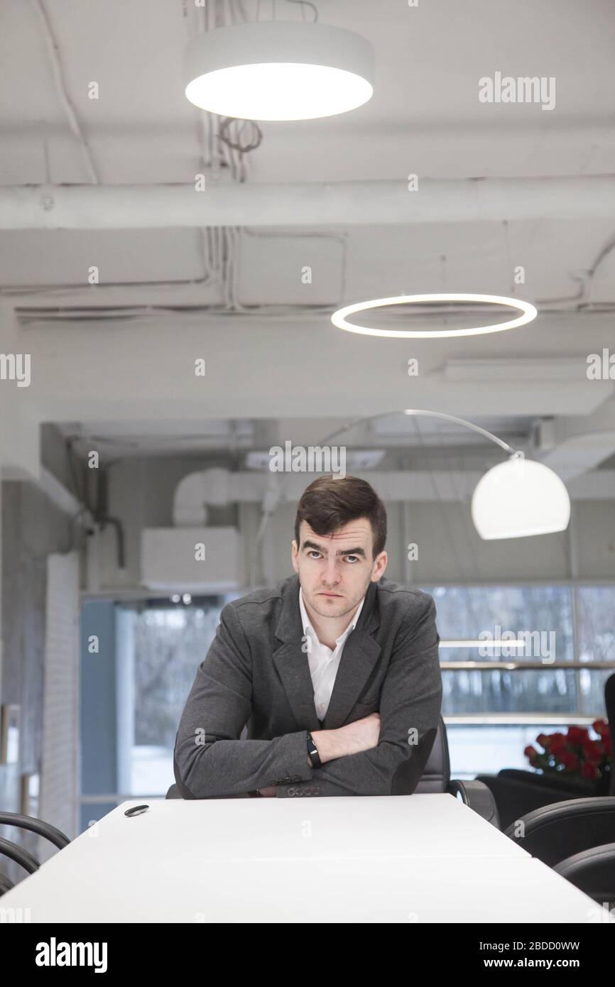 A young businessman works with documents at a white table in a modern interior Stock Photo