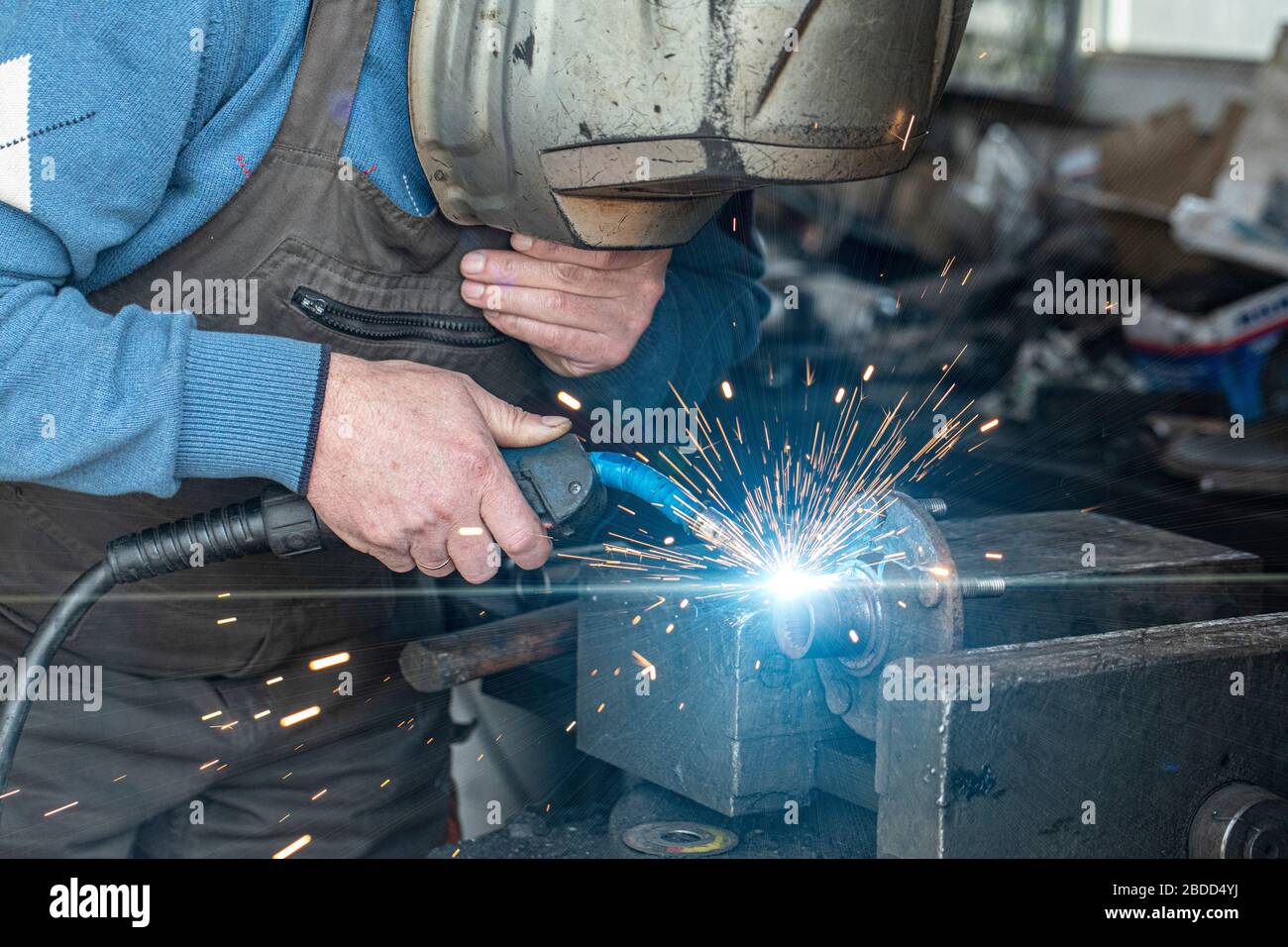 Locksmith welder welds a workpiece in a workshop. Stock Photo
