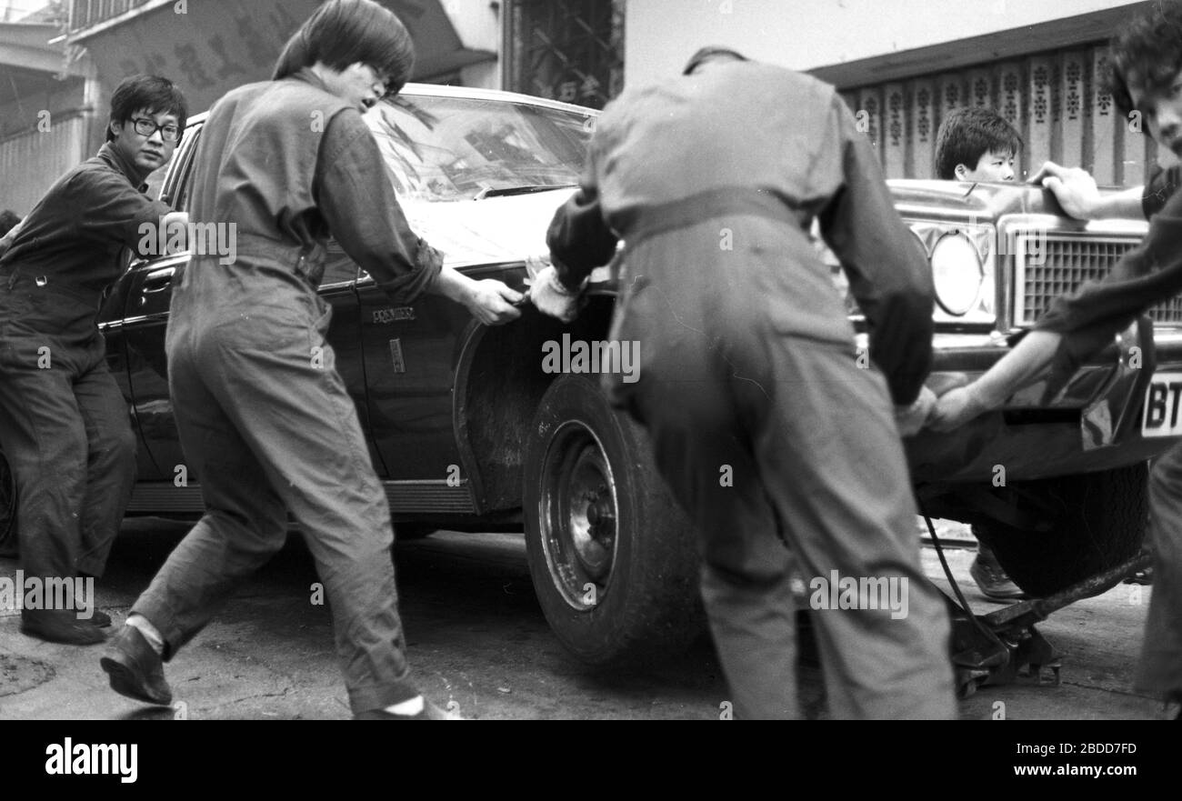 Emergency services including fire crews attend a building fire in Kennedy Street, of Queen's Road East on Hong Kong Island in 1979 as a team of workers in overalls try to bump a Chrysler Premier car to safety. Photo by Tony Henshaw Stock Photo