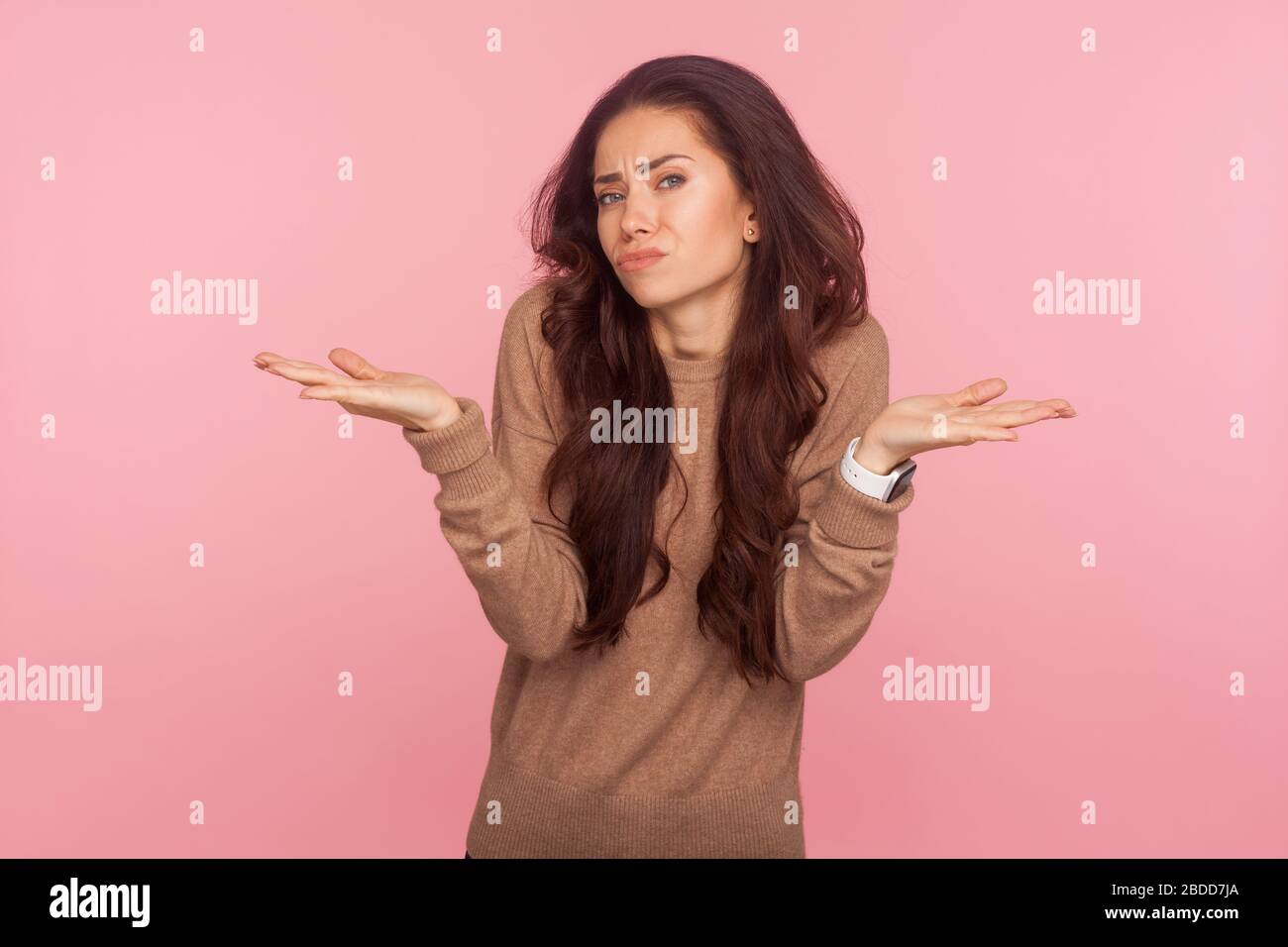 Don't know, maybe, who cares! Portrait of clueless confused young woman with brunette wavy hair looking embarrassed and disinterested in question, hes Stock Photo