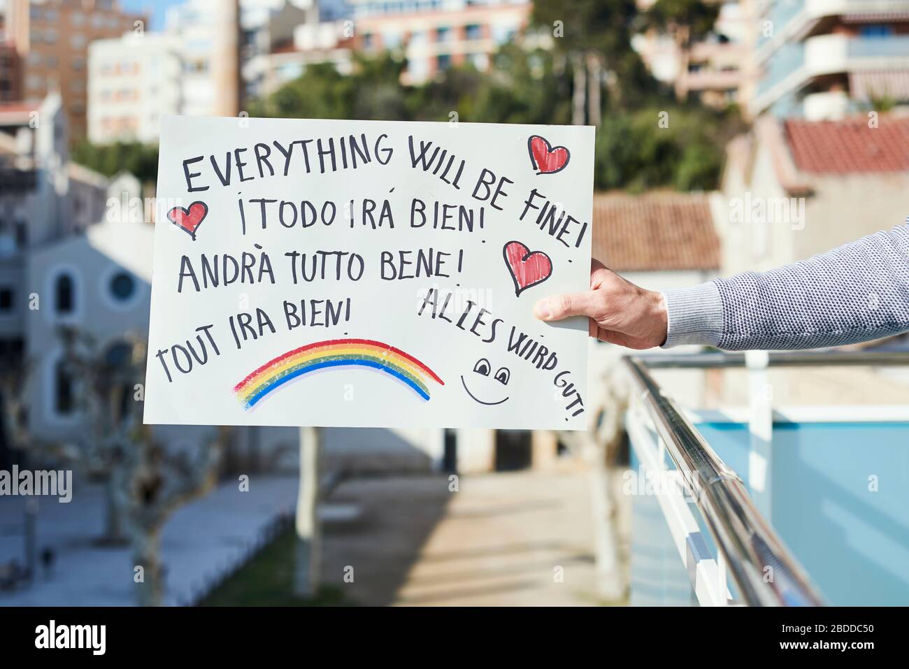 man showing a homemade sign with the text everything will be fine in different languages, such as Italian, German or French, as a message of hope duri Stock Photo