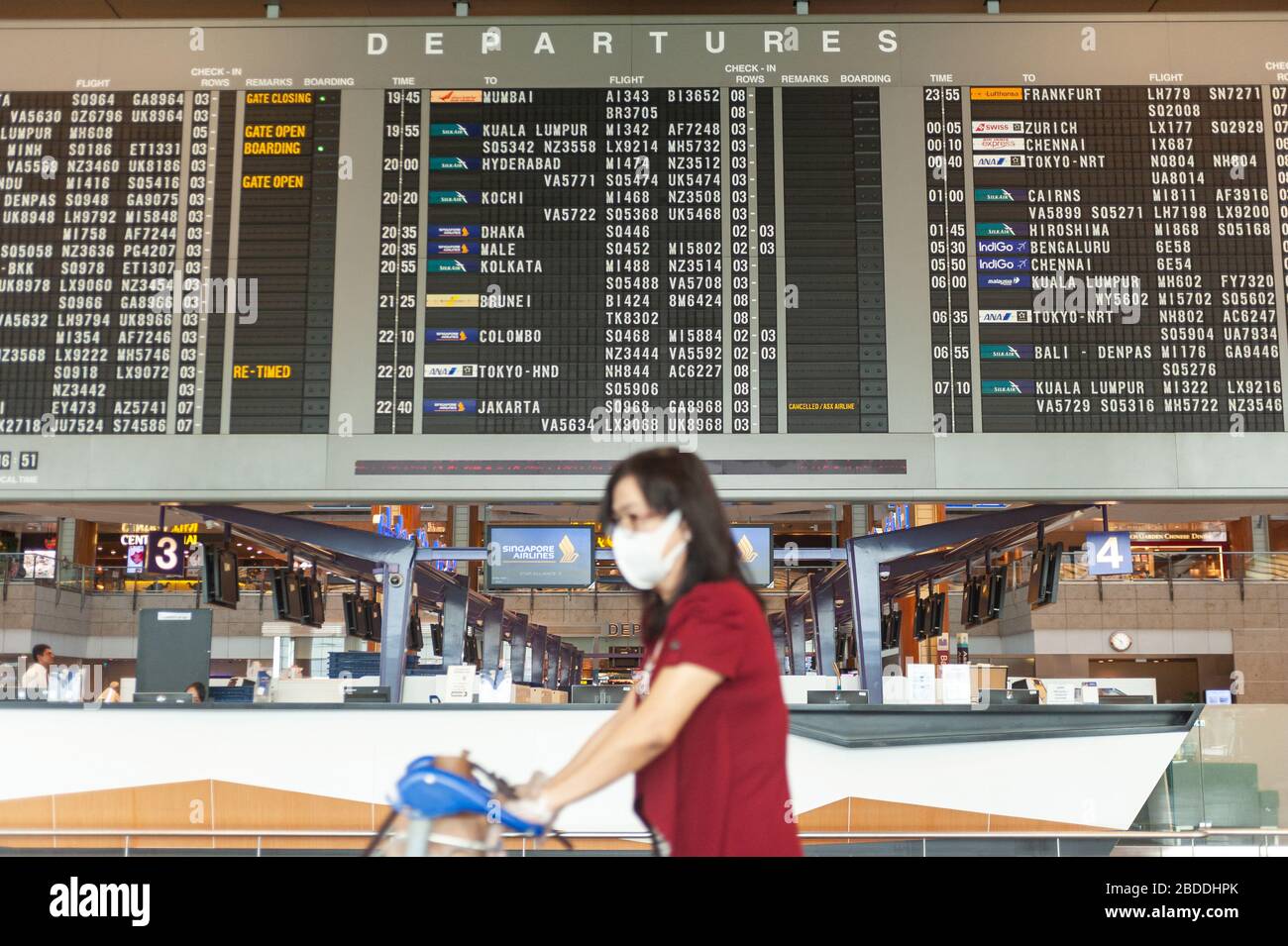 18.03.2020, Singapore, , Singapore - A woman walks past a display board with flight information in the departure lounge of Terminal 2 at Changi Airpor Stock Photo