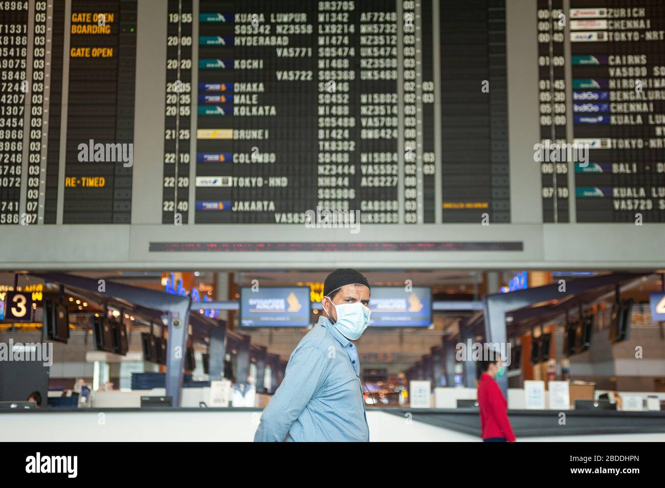18.03.2020, Singapore, , Singapore - A man walks past a display board with flight information in the departure lounge of Terminal 2 at Changi Airport Stock Photo