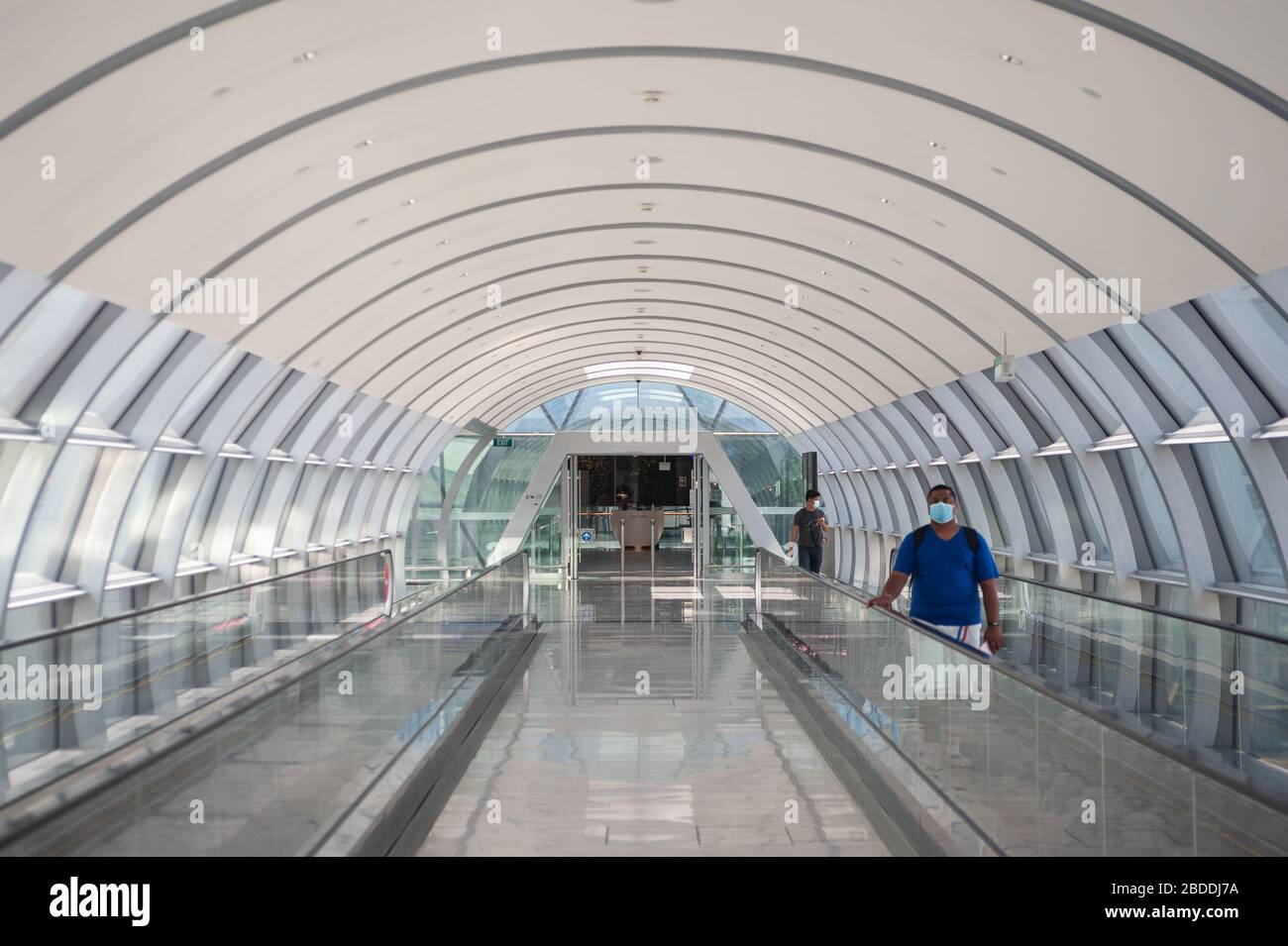 28.03.2020, Singapore, , Singapore - Two men are walking along the connecting bridge between Jewel Terminal and Terminal 2 at Changi Airport, wearing Stock Photo