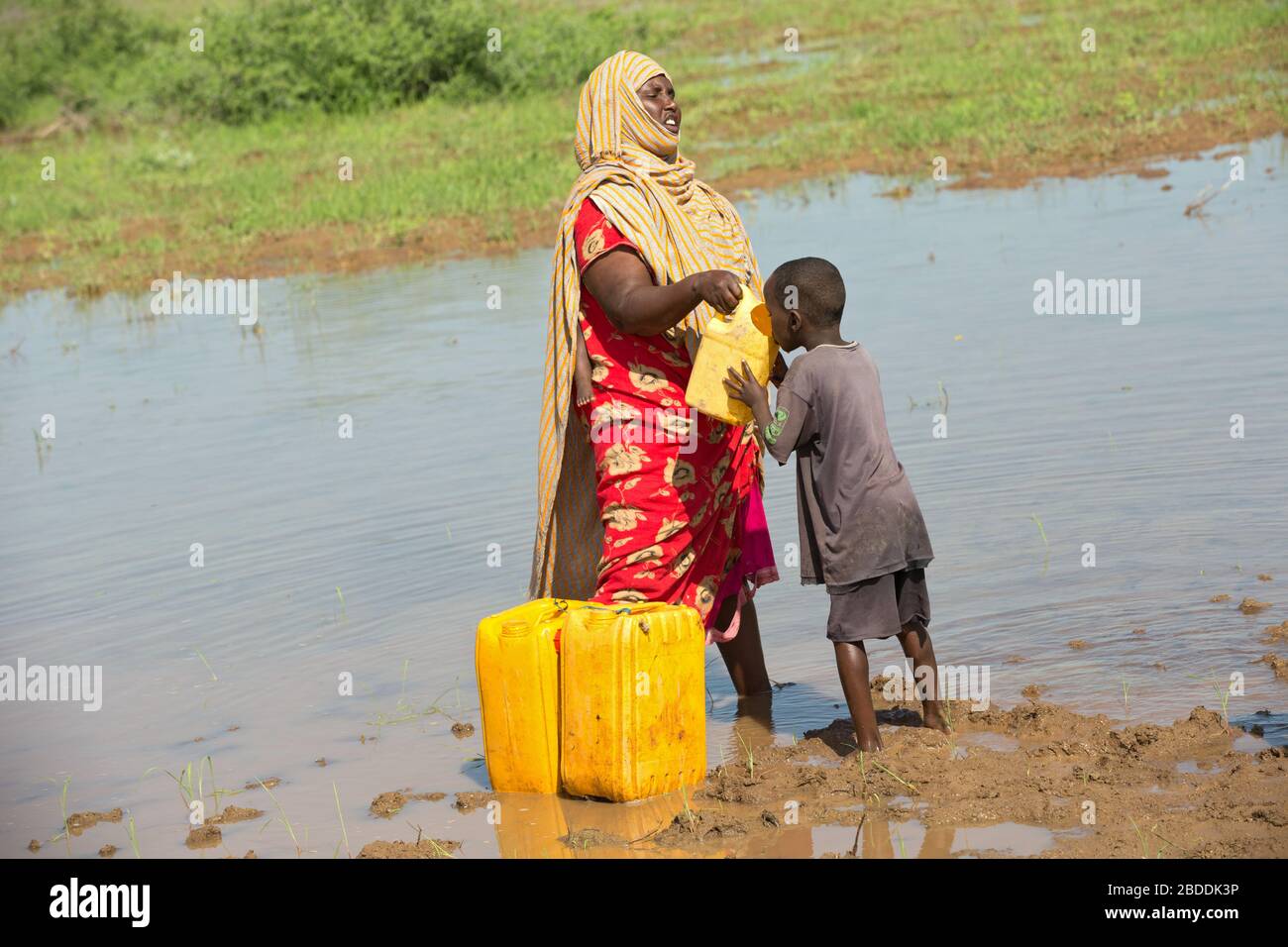 14.11.2019, Gode, Somali Region, Ethiopia - A woman draws water from a waterhole and gives it to one of her children to drink. Project documentation o Stock Photo