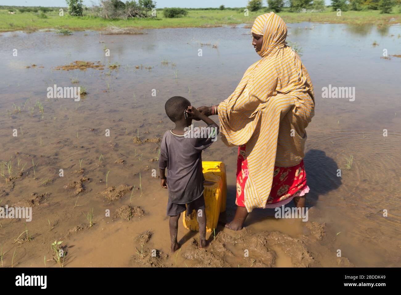 14.11.2019, Gode, Somali Region, Ethiopia - A woman holds a mobile phone to her boy's ear to make a phone call. Natural watering place. Project docume Stock Photo