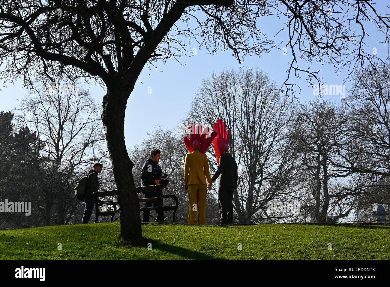 Man and Woman walking in park with large foam hand on their heads Stock Photo