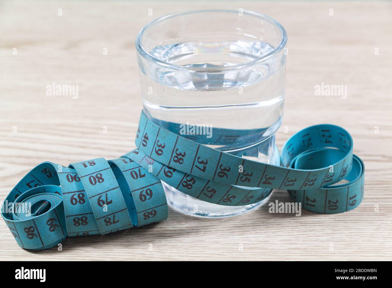 https://c8.alamy.com/comp/2BDDWBN/sewing-meter-around-a-glass-of-water-as-concept-for-diet-2BDDWBN.jpg