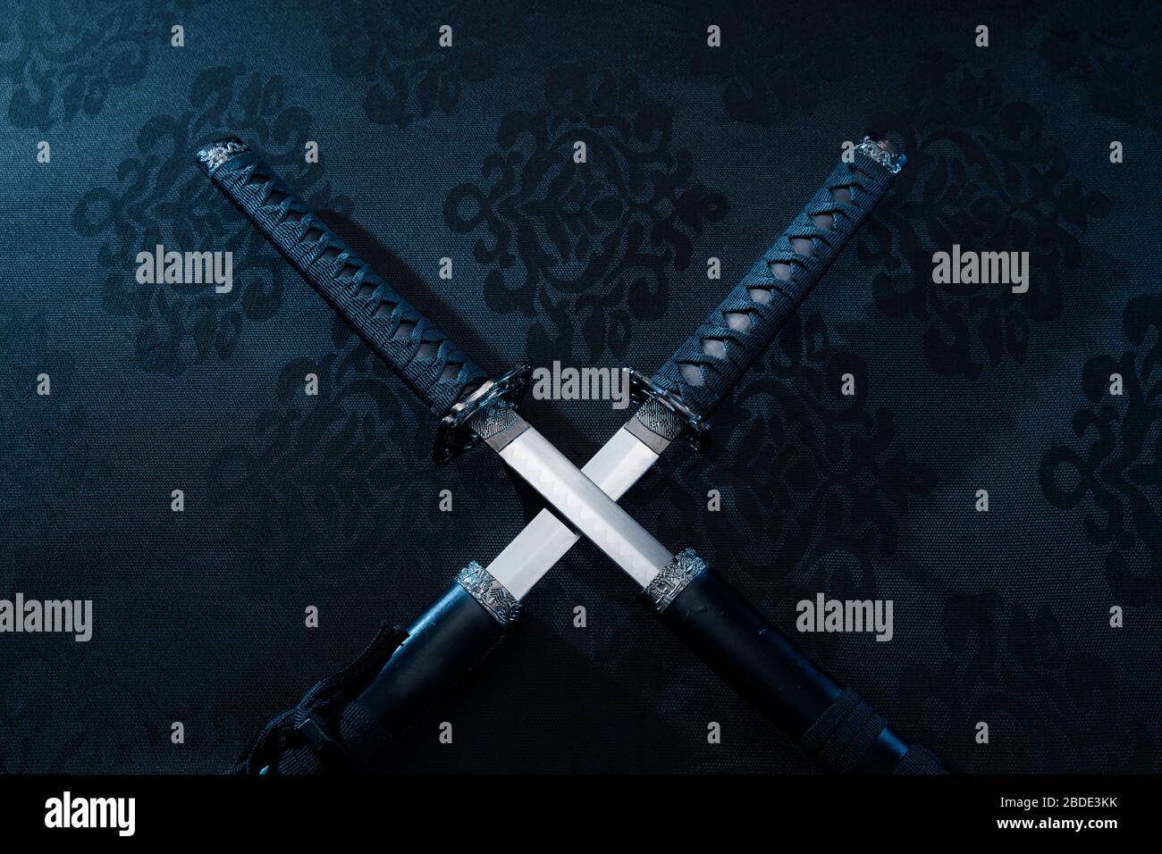 Two katanas, partially drawn blades on fabric with symbols Stock Photo