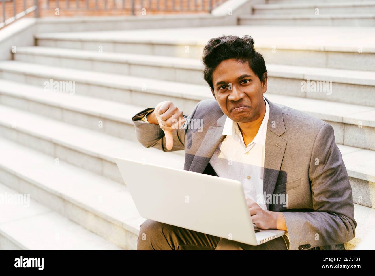 Young handsome Indian man in a white shirt and a business suit is sitting  Stock Photo
