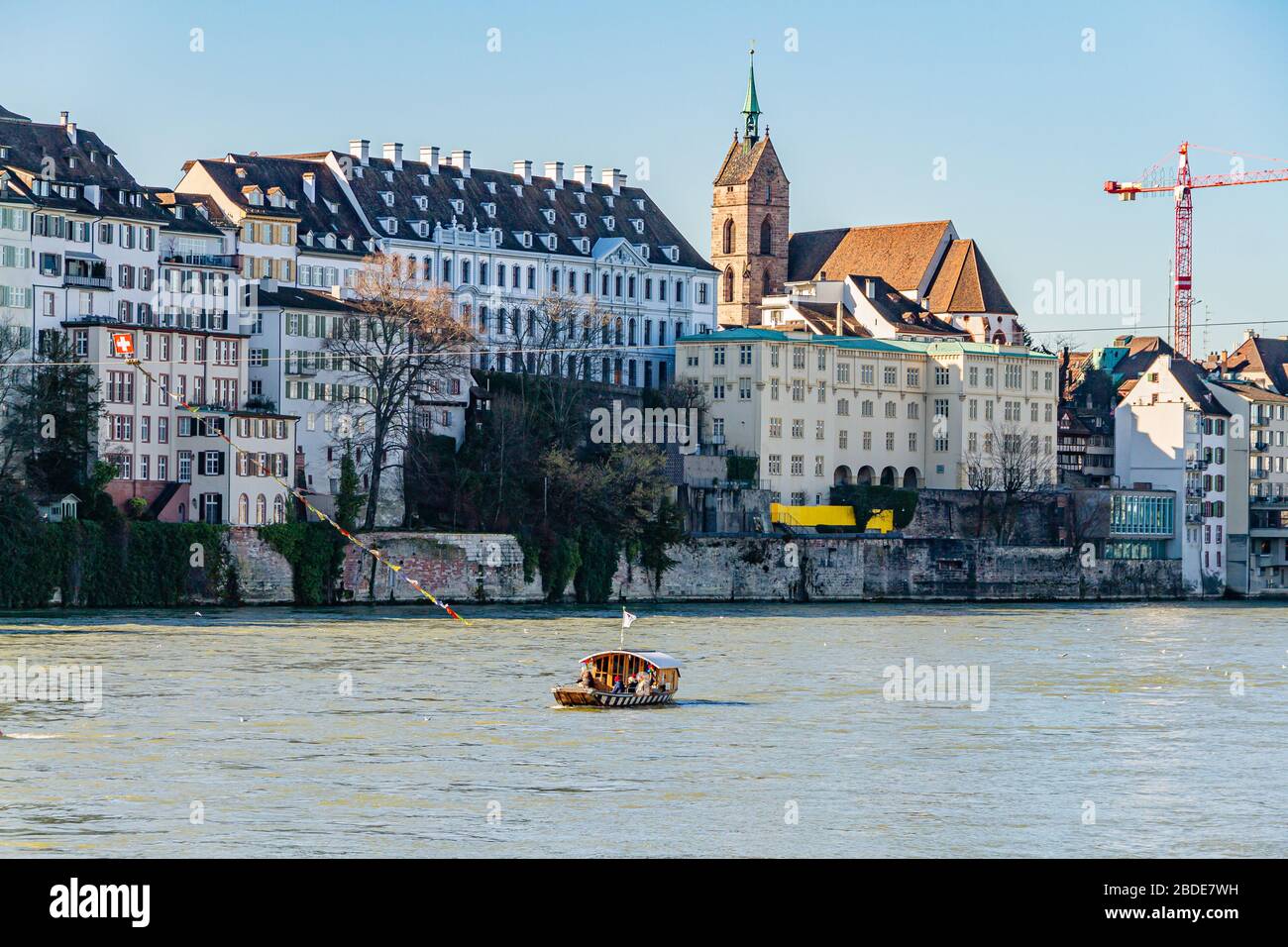 One of four cable ferries that cross the river Rhine in central Basel, with the minster / cathedral behind. Basel, Switzerland. February 2020. Stock Photo
