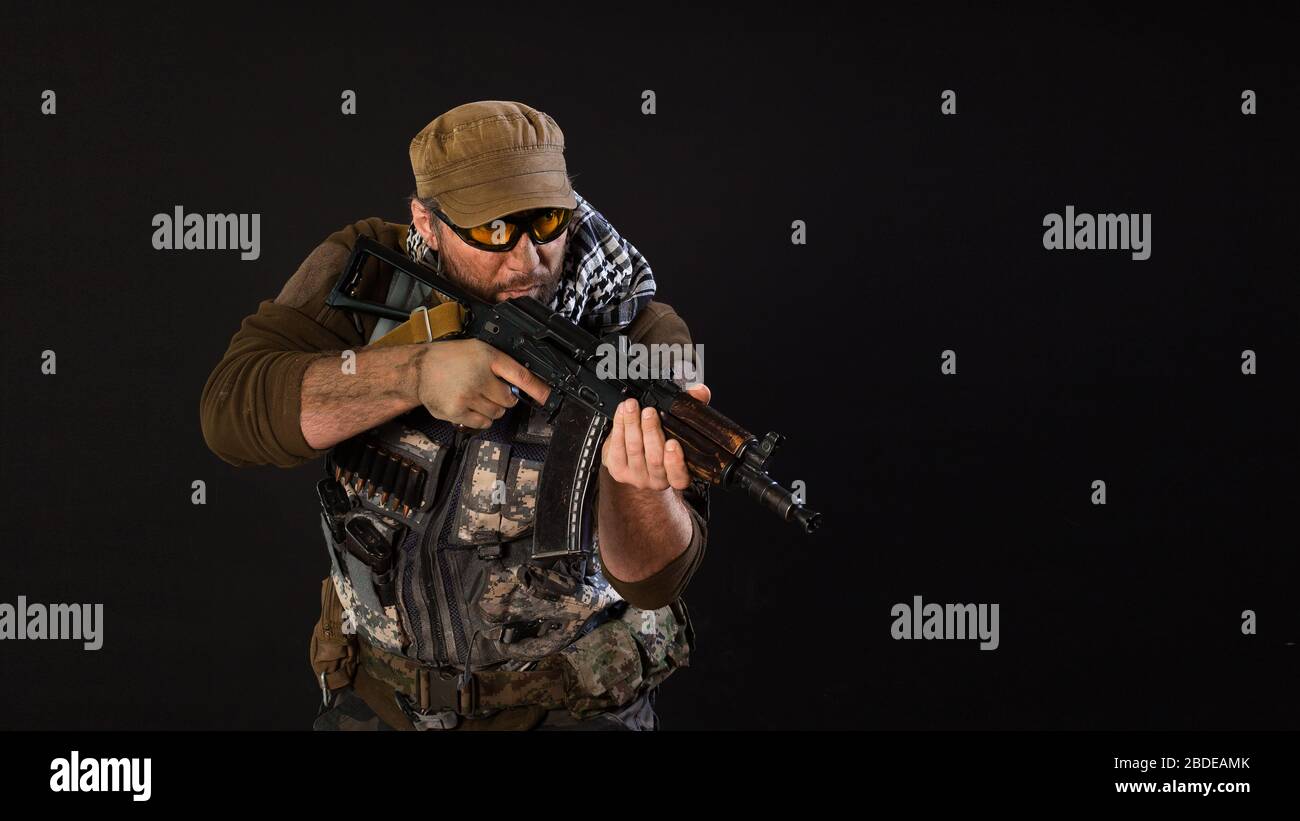 Soldier mercenary with a gun aiming at the enemy. Photo on a dark background. Modern private army concept. Stock Photo
