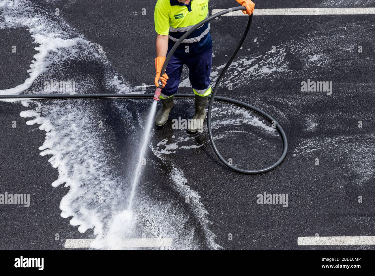 Council worker hosing down the streets with a disinfectant wash during the coronavirus lockdown, Playa San Juan, Tenerife, Canary Islands, Spain Stock Photo