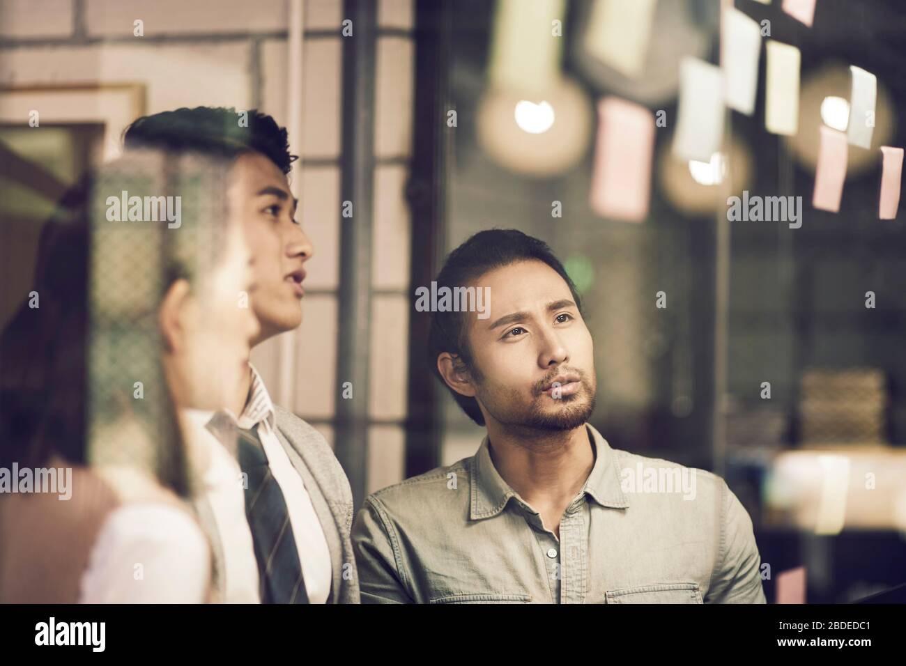 three asian small company businesspeople young entrepreneurs meeing discussing in office using sticky notes Stock Photo