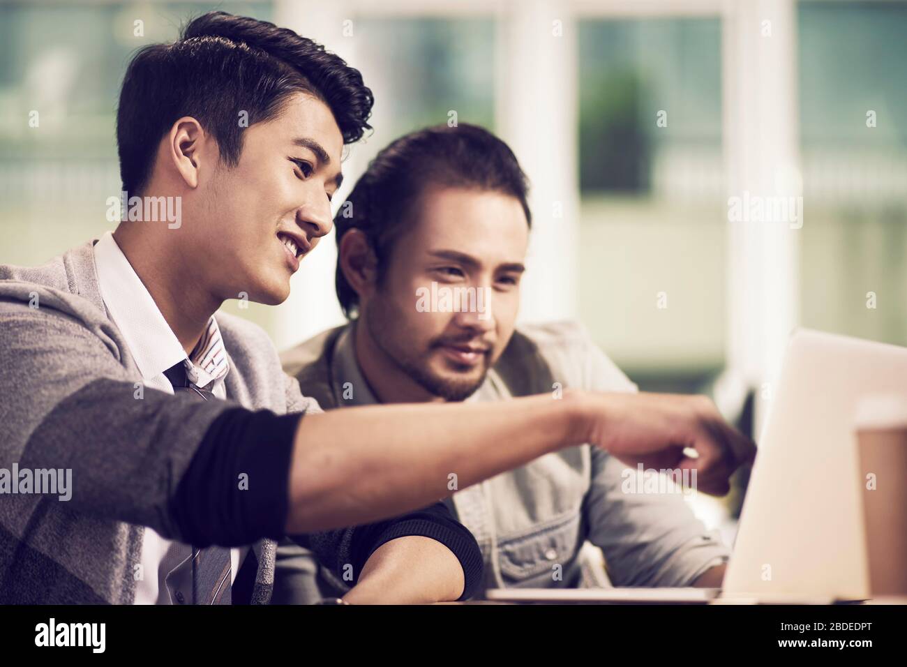 two young asian business teammates colleagues working together in office using  laptop computer Stock Photo
