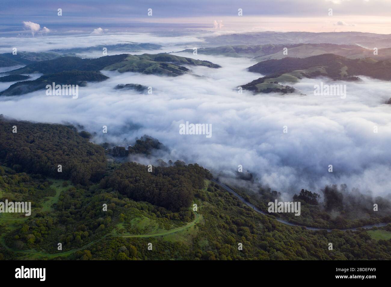 Early morning light illuminates fog as it rolls through valleys in Northern California. Just west of these hills and valleys is San Francisco Bay. Stock Photo